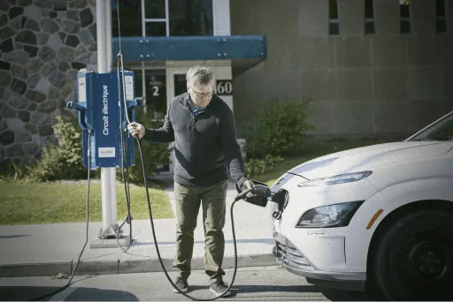 Driver charging an electric car at a Circuit électrique station